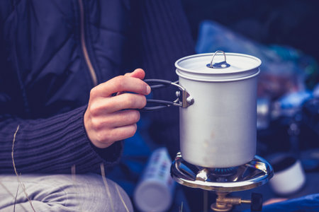 Young woman is camping and cooking on a portable stove