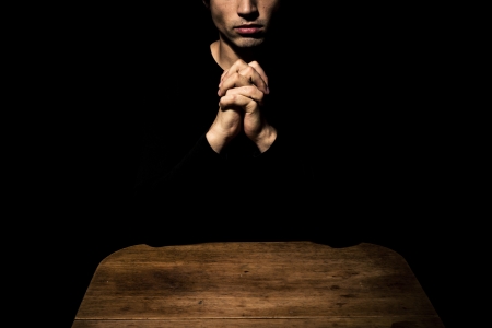 Man at table is praying in the darkの写真素材