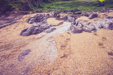 Small stream on a shingle beach with rural landscape in distanceの写真素材