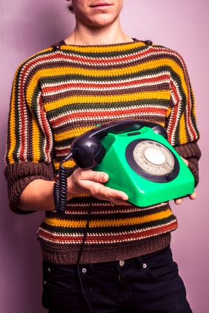 Young woman in colorful jumper holding an old telephoneの写真素材