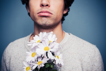 Sad young man with a bouquet of flowersの写真素材