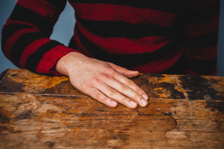 Young man resting his hand on a deskの写真素材
