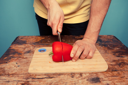 Young man is chopping a red pepperの写真素材