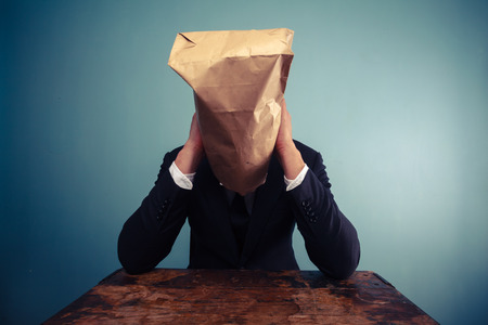Businessman with bag over his head is upsetの写真素材