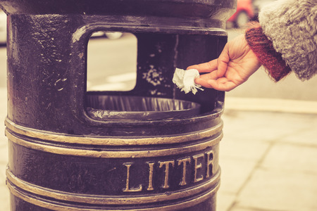 A woman is throwing something in a litter bin at the parkの写真素材