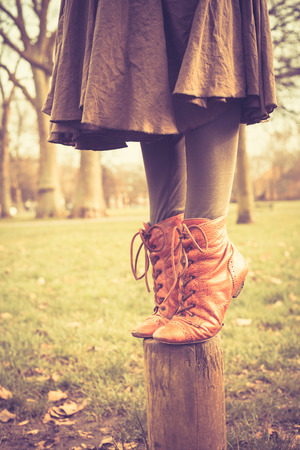 Closeup on a woman's feet as she is balancing on a wooden post in the parkの写真素材