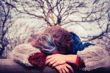 A Young woman is leaning on a wooden beam in the parkの写真素材