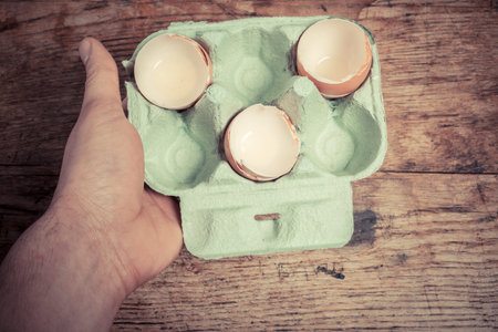 Hand holding a tray of egg shells at a table
