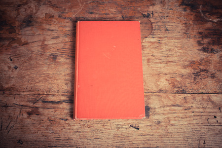 A red book lying on an old wooden tableの写真素材
