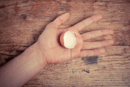 A man is holding an egg shell in his hand at a table