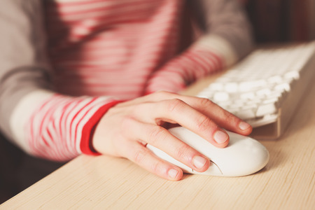 Closeup on the hand of a young woman using a computer mouseの写真素材