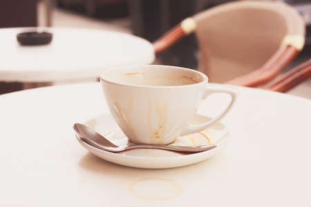 Dirty coffee cup and saucer at a cafe outside on a tableの写真素材