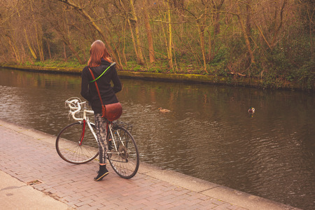 A young woman is on her bicycle by the canalの写真素材