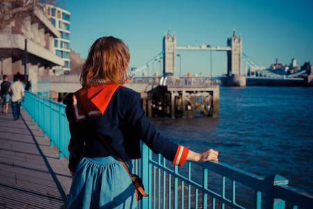 Young woman is standing on the bank of the river Thames in London on a sunny dayの写真素材