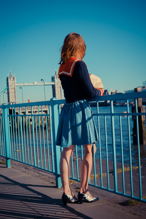 Young woman is standing on the bank of the river Thames in London on a sunny dayの写真素材