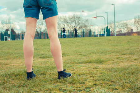 Young woman standing on grass in parkの写真素材
