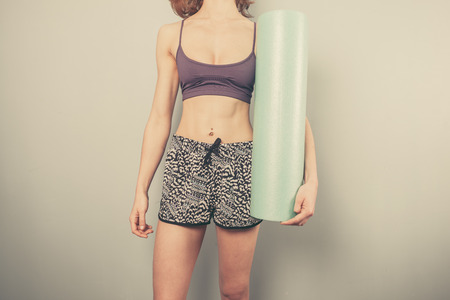 Athletic young woman is holding a foam roller for exerciseの写真素材