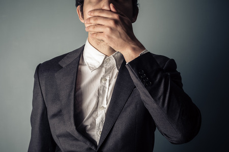 Shocked young businessman covering is mouthの写真素材