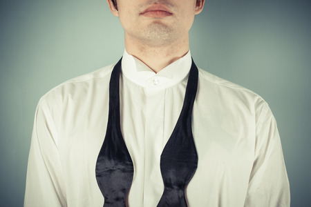 Young man is showing how to tie a formal bow tieの写真素材