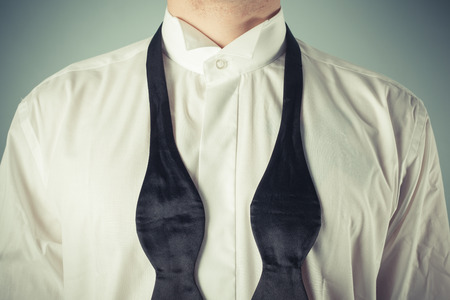 Young man is showing how to tie a formal bow tieの写真素材