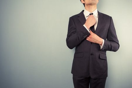 A young businessman is adjusting his tieの写真素材
