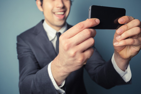 Young businessman is taking a selfie with his smart phoneの写真素材