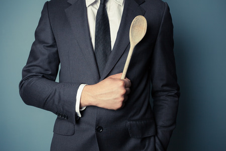 Young businessman is holding a wooden spoonの写真素材
