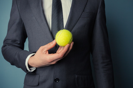Young businessman is holding a tennis ballの写真素材