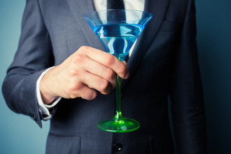 Young businessman is holding a tall cocktail glassの写真素材