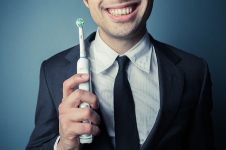 Young businessman is brushing his teeth with an electric toothbrushの写真素材