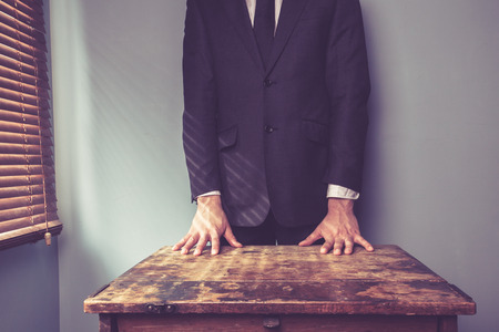 Businessman is standing behind a desk by the windowの写真素材