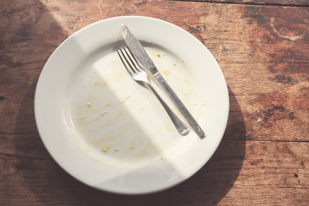 Dirty plate and cutlery on a wood tableの写真素材