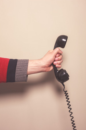 The hand of a man is holding a retro telephone receiverの写真素材
