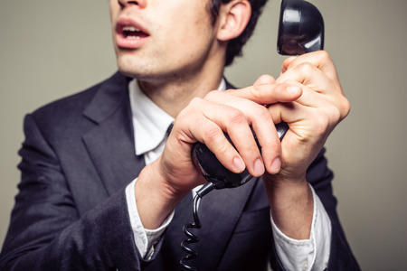 Businessman is covering the phone to speak in private to someone in the roomの写真素材