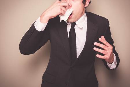 Businessman with a cold is sneezingの写真素材