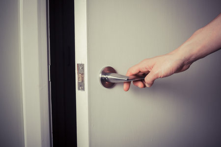 Closeup on the hand of a woman as she is opening a door at night