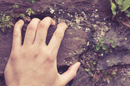 A man's hand is grabbing onto a rock
