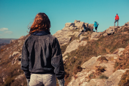 Youn woman is trekking in the mountains and watching fellow walkers in the distanceの写真素材