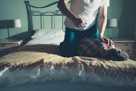 A man is beating his wife on a bedの写真素材