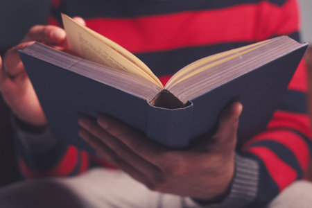Closeup on a man reading a big heavy book
