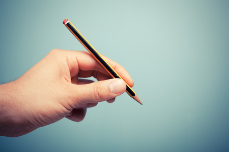 A hand is holding a pencilの写真素材