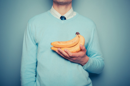 A young man is holding a bunch of bananasの写真素材