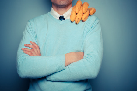 A young man with a bunch of bananas on his shoulderの写真素材