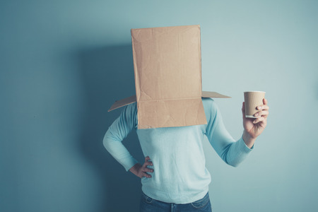 A man with a cardboard box on his head is holding a paper cupの写真素材