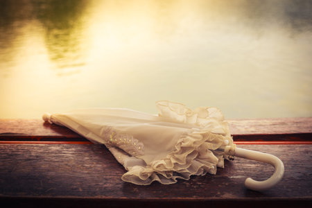 Vintage umbrella on a wooden table by a lake in the afternoonの写真素材