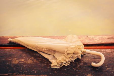 Vintage umbrella on a wooden table by a lake in the afternoonの写真素材
