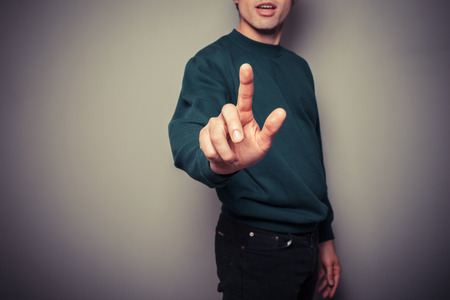 A young man is pointing or pushing a button with his fingerの写真素材