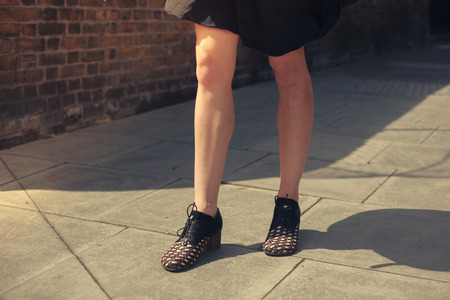 A young woman with bare legs is standing in the street on a sunny dayの写真素材