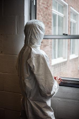 A scientist wearing a boiler suit is standing by  a windowの写真素材
