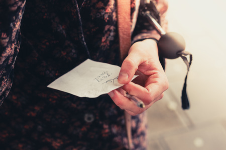 Young woman is holding a note with a phone number written on itの写真素材
